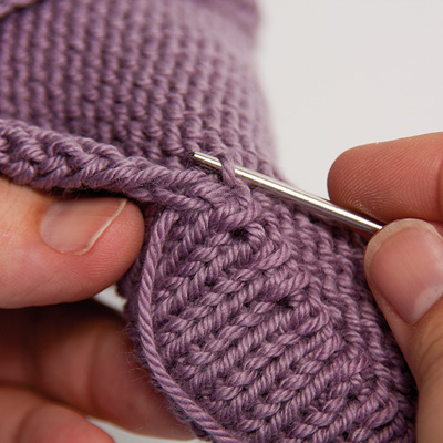 Rabattre la bordure sur l’envers et coudre les boucles de montage sur l’envers au point de surjet.